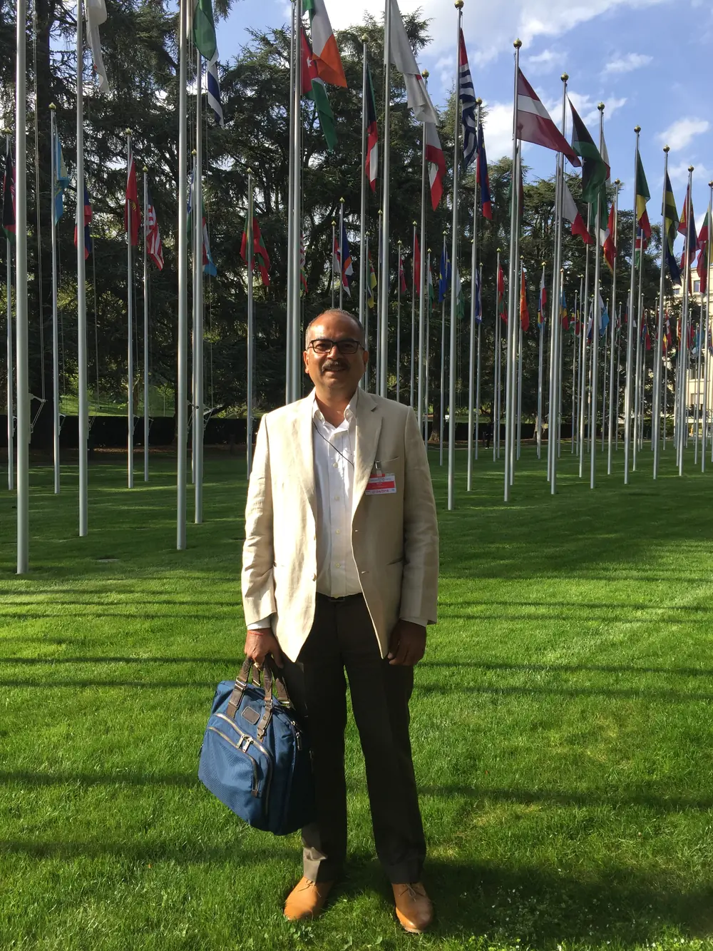 Sachin Mehta at the United Nations in Geneva, standing before the avenue of member-state flags.